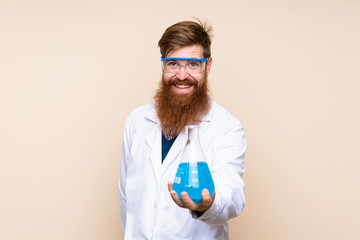 Redhead man with long beard over isolated background with a scientific test tube