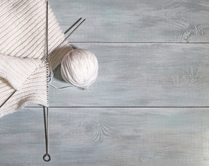 Knitting white threads on a wooden background