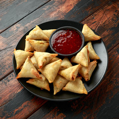 Fresh Indian Samosa with dipping sweet chili sauce on wooden table