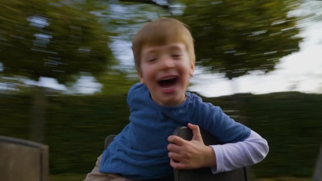 A cute boy happily spinning on a Merry-Go-Round