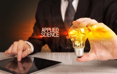 Businessman holding lightbulb with APPLIED SCIENCE inscription, Business technology concept