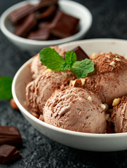 Chocolate Ice Cream with dark chocolate bars and hazelnuts in a white bowl