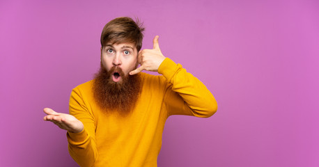Redhead man with long beard over isolated purple background making phone gesture and doubting