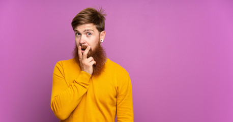 Fototapeta na wymiar Redhead man with long beard over isolated purple background surprised and shocked while looking right