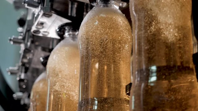 Plastic bottles automatically pass across conveyor and are filled carbonated beverages. Food industrial production on bottling and packaging of liquid on modern equipment. Bottling plant concept.