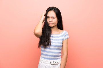 Teenager asian girl over isolated pink background having doubts