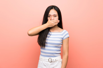 Teenager asian girl over isolated pink background covering mouth with hands