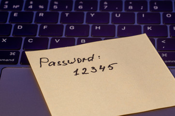 A very weak, simple and widespread password is written on a sticker that lies on the laptop keyboard. Password Security Weakness Concept. Bad password. Typical information security failures. 