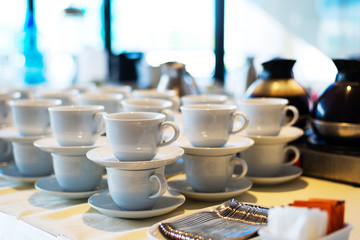Coffee or tea ceramic cup stacked on buffet table that ready to serve to participant / attendees in seminar or cafe