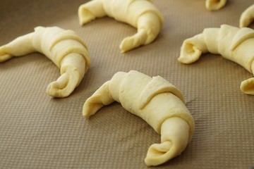 Uncooked croissant on brown paper. Preparing croissant to bake in stove. 