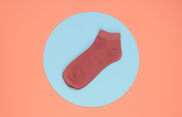 Pink socks on pink background with blue circle in the middle. Minimalistic fashion still life. Top view