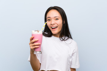 Teenager asian girl holding a strawberry milkshake with surprise and shocked facial expression