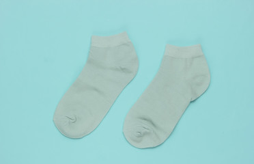 Mint green socks on blue background. Pastel color trend. Top view