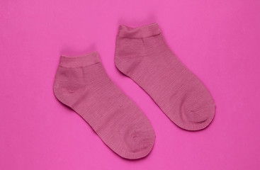 Pink socks on pink paper background. Top view