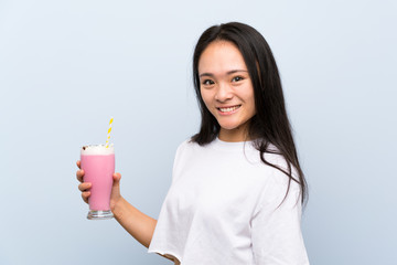 Teenager asian girl holding a strawberry milkshake smiling a lot