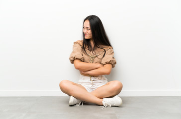 Teenager asian girl sitting on the floor looking to the side