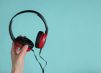 Female hands hold stylish wired headphones on a blue pastel background. Music fan, DJ. Top view.