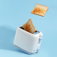 Appetizing toasted toasts fly out of the toaster. blue background
