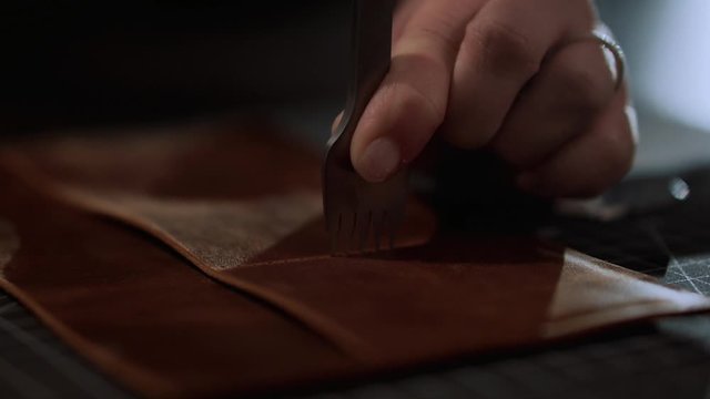 Close up craftswoman working with leather belt. Shoe production process in factory. Close up leather craftsman working with natural leather using hammer. Handmade concept, Working process with leather