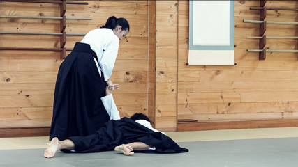 A Lady Aikido Martial Artists in Traditional Costume Illustrating Wrist / Hand / Arm Lock Technique to Control The Opponent.