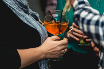 woman holding glass of refreshing orange alcoholic cocktail in the bar