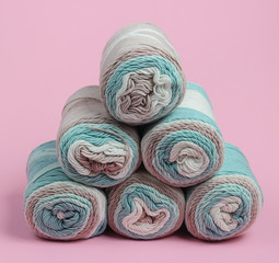 Stack of skeins of woolen threads close-up on pink pastel background