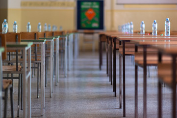 Exam examination room or hall set up ready for students to sit test. multiple desks tables and chairs. Education, school, student life concept.
