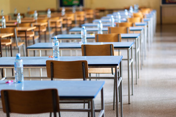 Exam examination room or hall set up ready for students to sit test. multiple desks tables and chairs. Education, school, student life concept.