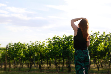 Young redhead woman standing in vineyard. Enjoy every moment of life. Solo woman traveler enjoying life. Great time while traveling. 