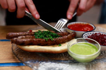 A man cutting and eating sausages in restaurant. 