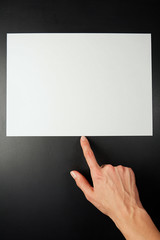 Index finger points to a blank sheet of white paper