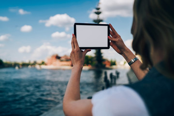 Back view of female person trying to make good picture on digital tablet with mock up screen for your promotional.Cropped image of woman's hands holding gadget with copy space for advertising