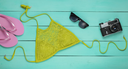 Summer fun background. Woman's swimsuit and beach accessories on blue wooden background. Overhead view of woman's swimwear. Vacation on the beach. Flat lay, top view.