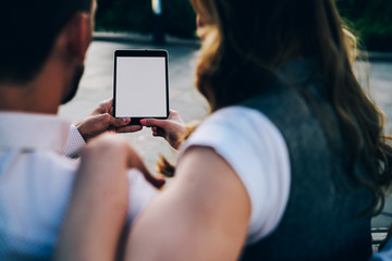 Back view of man and woman holding digital tablet with copy space screen for your advertising message.Cropped image of male and female resting outdoors using touch pad with mock up for promotional