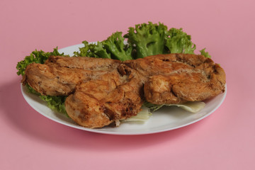 Grilled chicken breasts with lettuce on a plate on a pink pastel background