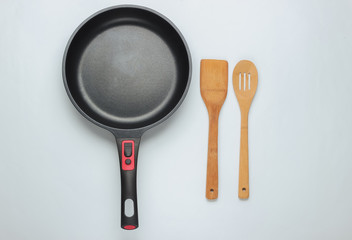Non-stick pan with cooking spatula on white background. Cooking minimalism concept. Studio shot. Top view