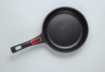 Frying pan with a non-stick coating on white background. Cooking minimalism concept. Top view