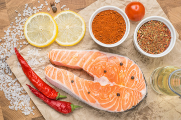 Raw fresh Salmon fillet steak slices with lemon, sol, tomato and ingredients for cooking, condiment. Fresh uncooked red fish, seafood. Top view