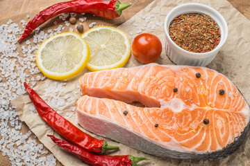 Raw fresh Salmon fillet steak slices with lemon, sol, tomato and ingredients for cooking, condiment. Fresh uncooked red fish, seafood. Top view