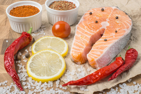 Raw fresh Salmon fillet steak slices with lemon, sol, tomato and ingredients for cooking, condiment. Fresh uncooked red fish, seafood. Top view