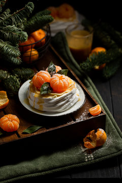 Tangerine Pavlova. Famous Delicious Dessert Of Meringue, Cream And Fruit. Christmas Look With Tangerines On The Background Of The Christmas Tree