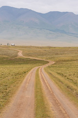 Obraz premium Dirt road in autumn field. Travel through countryside off road