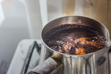 Barista preparing hot tasty drink from copper turk, boils water for coffee on small fire in cezve. Coffee turk made of organic copper, cezve to kitchen. Copper turk for real gourmet coffee at cezve