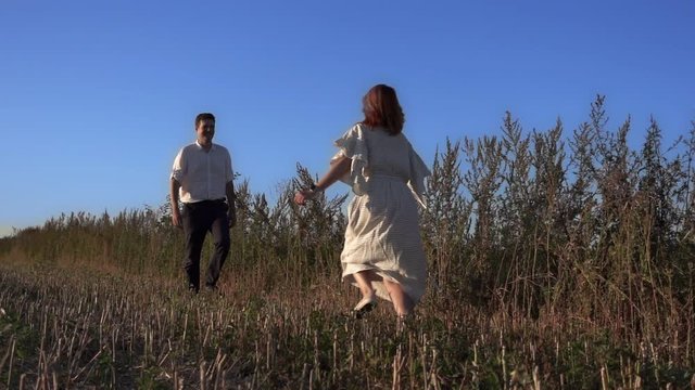 Romantic man catches his girlfriend in a jump and hugs her. Woman is running to her man, they hug and spin around on a outdoor. Theme of love and happiness of family. Slow motion at 250 fps.