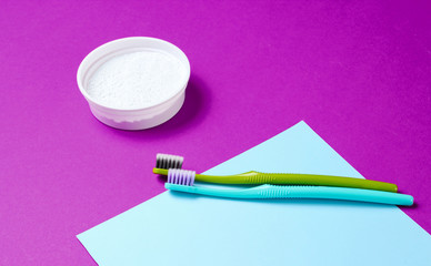 Two toothbrushes, tooth powder on pink blue paper background. Minimalism oral hygiene concept
