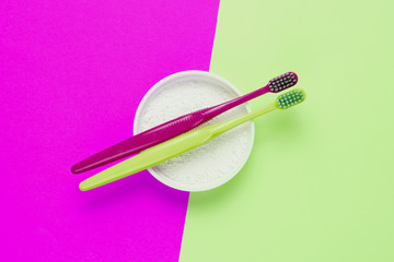 Two toothbrushes, tooth powder on pink green background. Minimalism oral hygiene concept. Top view