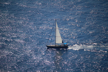 Aerial view at sailing yacht on the blue sea glistening in the sun