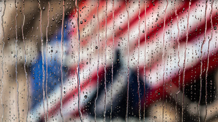 American Flag behind rain streaked glass. Flag is deliberately out of focus with the focus being on...