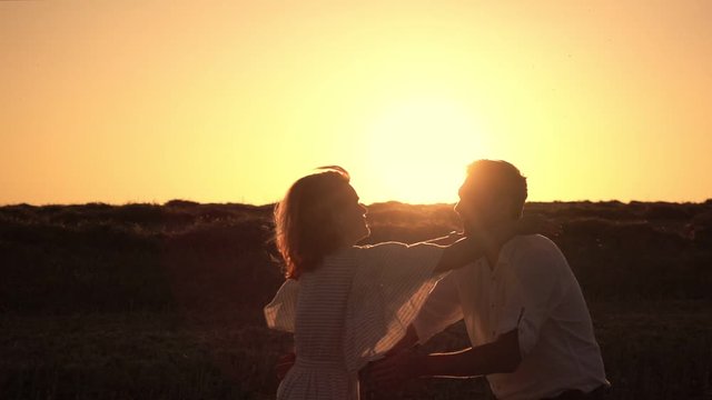 Girl jumps into her husband arms against romantic sunset background. Woman is running to her man, they hug and spin around on a outdoor. Theme of love and happiness of family. Slow motion at 250 fps.