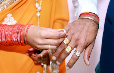 Indian Bride putting a wedding ring on groom's finger